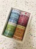 Set of colorful washi tapes in a box on a patterned background