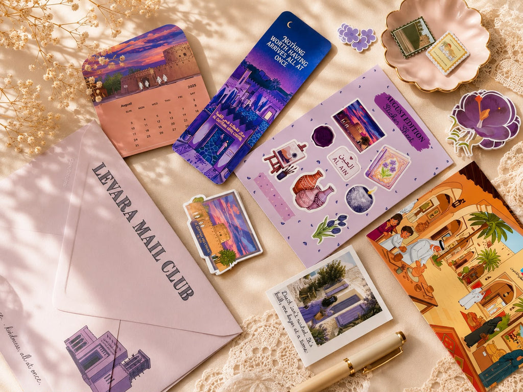 A flat-lay arrangement of stationery items on a beige fabric background with lace and dried flowers. Visible items include a lavender envelope printed 'LEVARA MAIL CLUB,' a purple calendar, a blue postcard, a lavender sticker sheet, small illustrated stickers, a postcard, a pen, and colorful illustrated cards or envelopes.