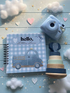 Levara baby book with blue checkered cover featuring a vintage car next to blue instant camera and wooden stacking toy