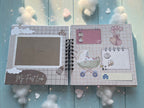 Levara baby book open to pages with space for photos and baby-themed illustrations on blue background
