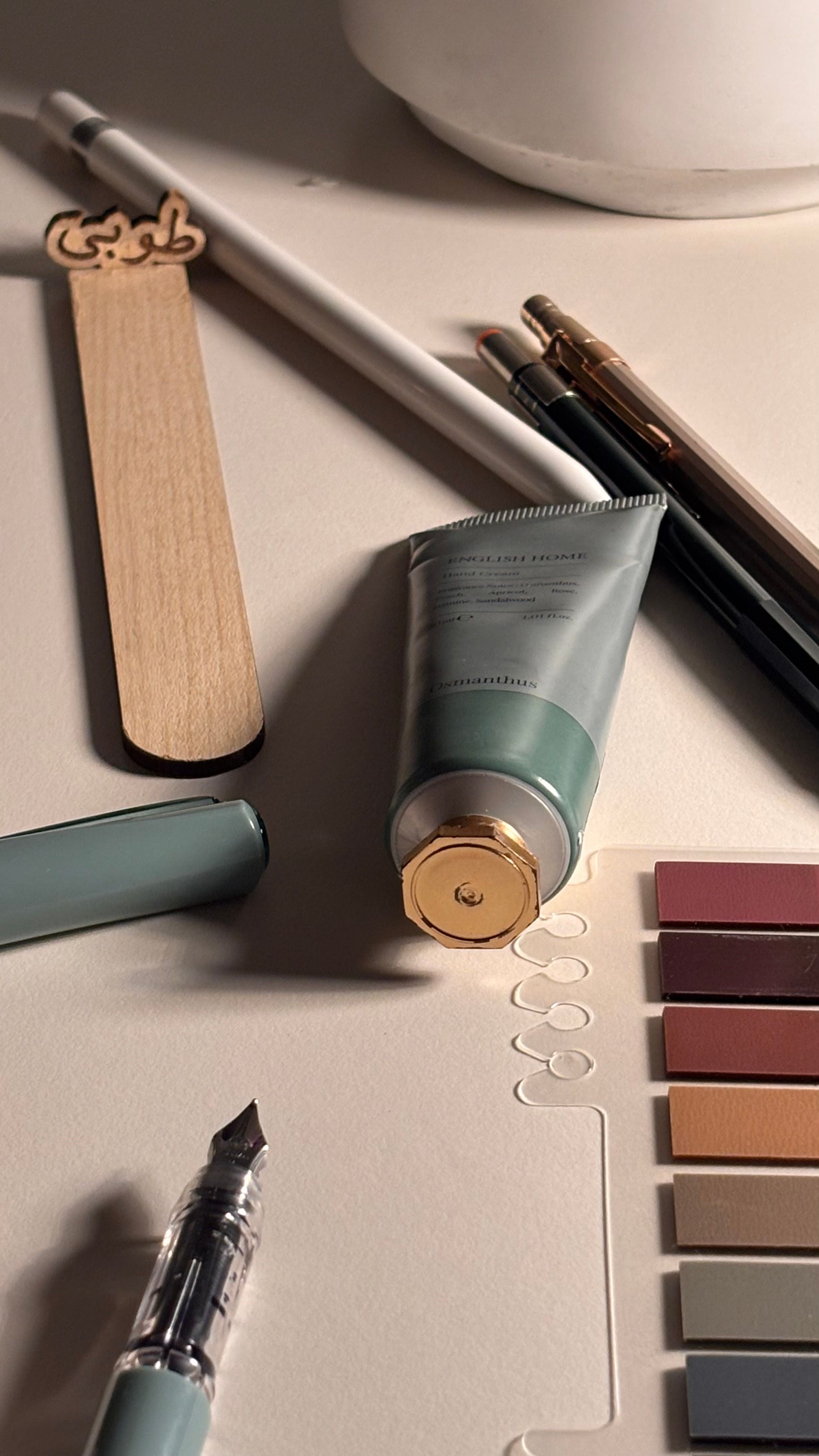 Stationery items including a tube of cream, pen, and markers on a light surface.