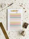 Notebook with colorful tabs on a terrazzo-patterned surface with stationery items.